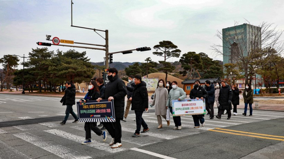 경주엑스포대공원 임직원들이 서문 입구 신호등 개통 행사 후 행사 알림판을 들고 횡단보도를 건너며 보행안전 퍼포먼스를 펼치고 있다.