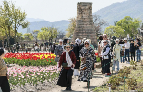 경주 동부사적지에서 외국인 관광객들이 첨성대를 배경으로 산책을 즐기고 있다.